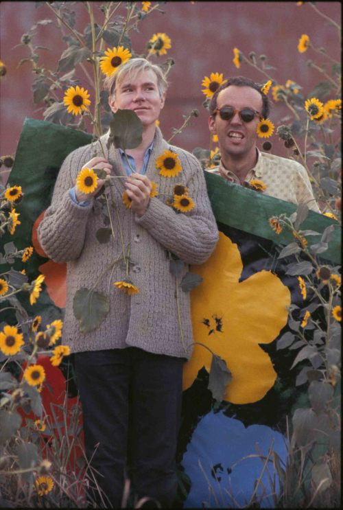 Andy Warhol in a field of black-eyed susans with Taylor Mead holding an early “Flowers&rd