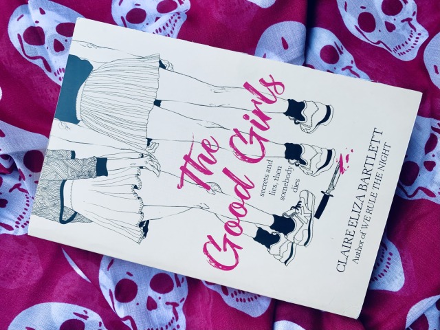 THE GOOD GIRLS (with cover art depicting the legs and feet of a group of young women standing together) against a backdrop of skulls. Hot pink appears on the book cover and in the background. Photo by AHS.