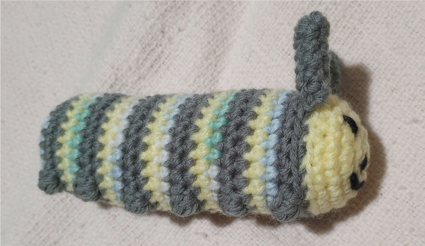 crochet caterpillar side view. Yellow, grey, and blue/green stripes.