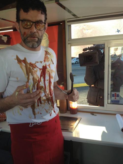 Stefan Karl covered in sauce inside of a hotdog stand.