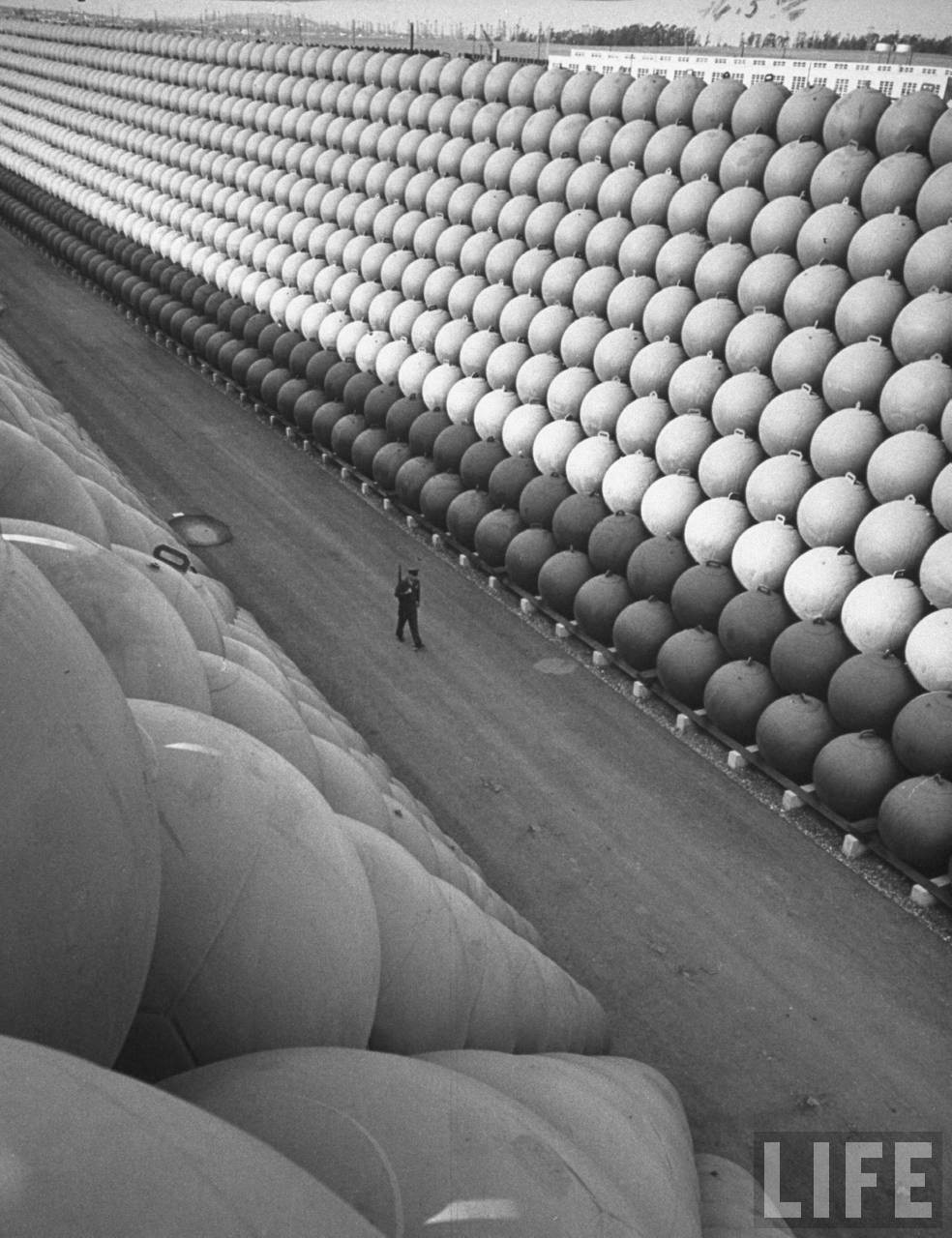 A security guard walking down US Highway 101 where there are towering stacks of hollow