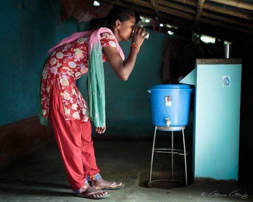 Manjali Hasda drinks clean water from the biosand water filter...
