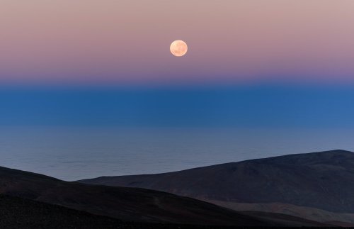 ​The full moon is setting over the Pacific Ocean, above the Earth’s shadow and the Atacama Des