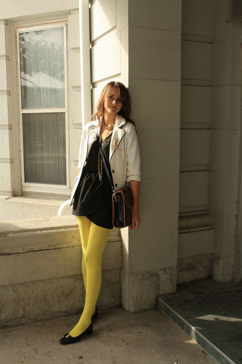 Bright yellow pantyhose, black dress and flots with white classic cut coat