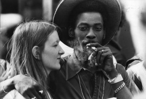 A young couple share a joint at Notting Hill Carnival 1980, west London.