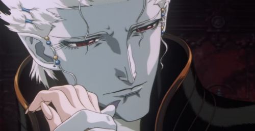 A very pretty vampire man with white hair and red eyes is looking at someone off screen while holding her hand up to his face. The image is cropped too closely to see the woman he is interacting with, but the vampire seems sad.