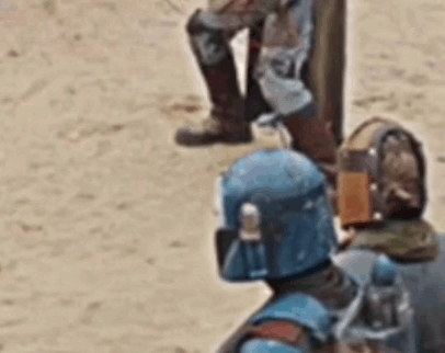a zoomed in gif from the mandalorian season 3. focused on a Mandalorian with an orange helmet, the back of which is open revealing cloth