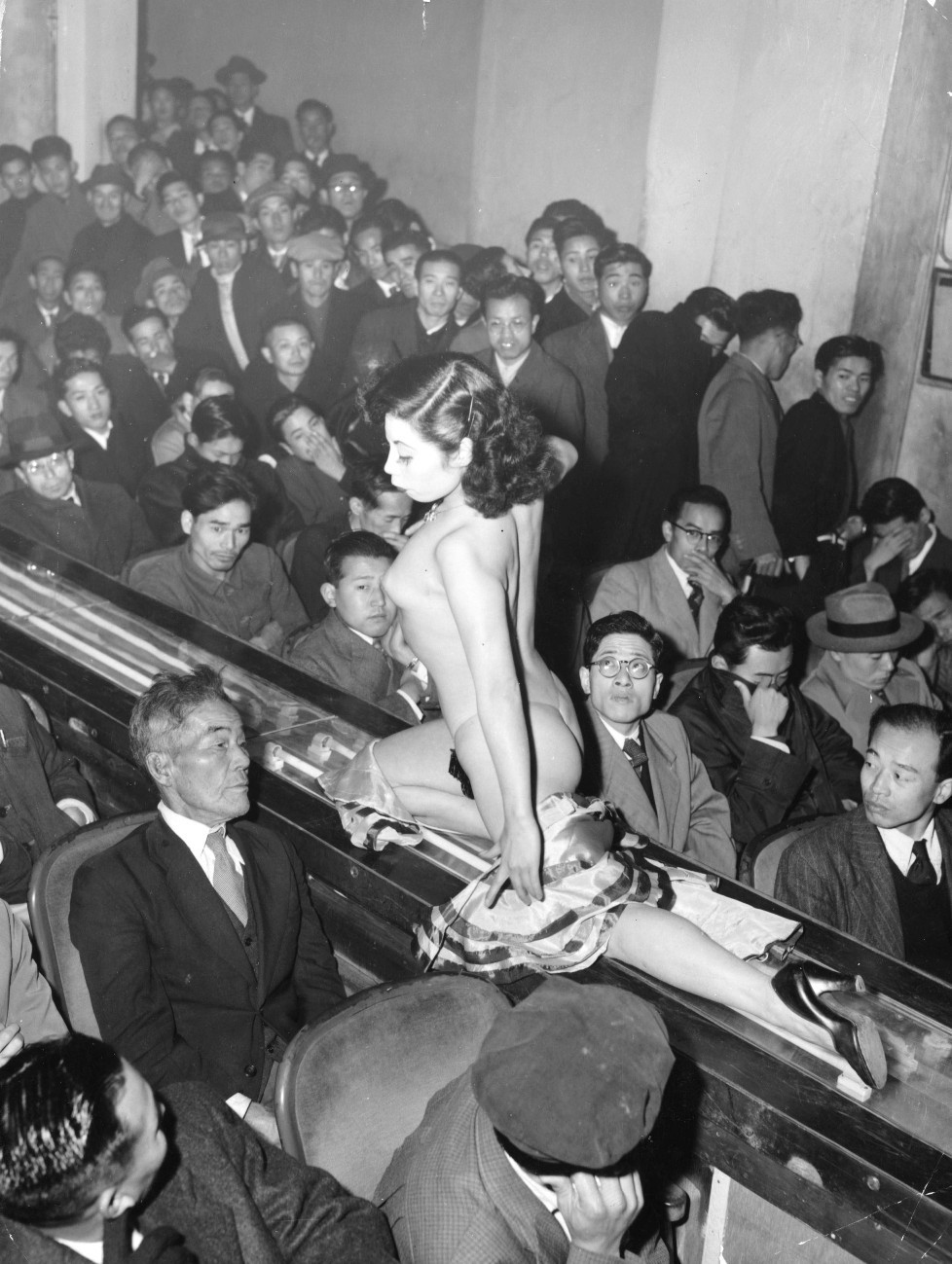 historicaltimes:  A stripper at a Tokyo striptease show is taken past the audience