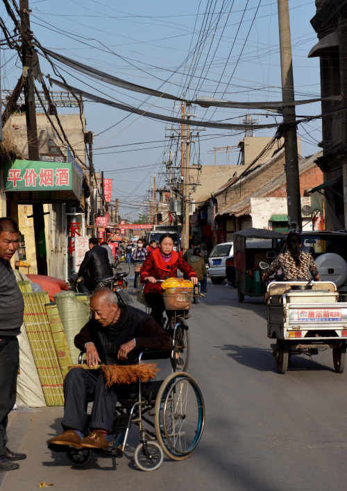 Busy street life for an older man in a wheelchair, Anyang, China.