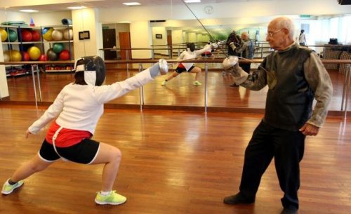 [ID: three photos of the same fencer; in the present day giving an epee lesson, standing in his coac