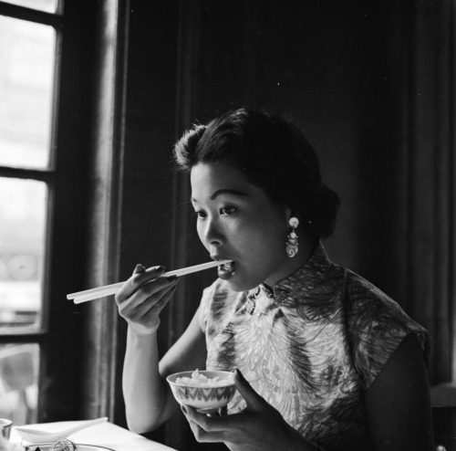 1955: A young woman eats a bowl of rice using chopsticks in Johnny Kan&rsquo;s famous Chinese re
