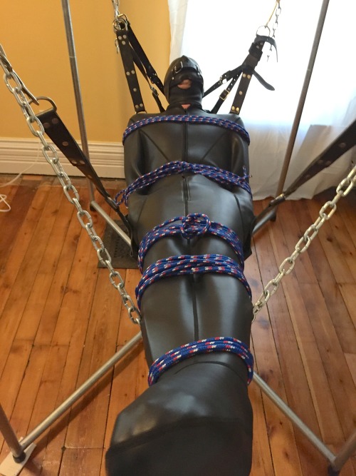 feelingknottycda:  A friendly British chap came over for a bit of fun.  He has an UnderArmour bodysuit and a chastity cage on under the neoprene sleepsack, securely bound to my sling.  I couldn’t quite make out the specifics of his moans under that