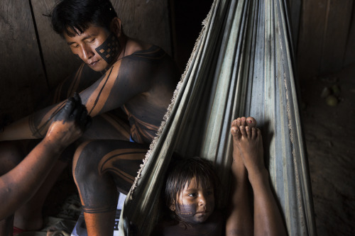 Xikrin men and women gather in a house in the Amazon rainforest to have their bodies painted. The Xi