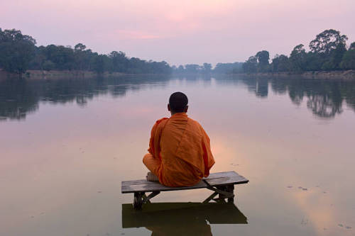 mvtionl3ss: Cambodia, Angkor Wat, Buddhist monk sitting on platform, in moat surrounding temple comp