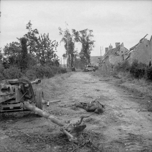 ironwarriors: On a road in Fontenay-le-Pesnel a dead nazi gunner lies beside his 75mm anti-tank