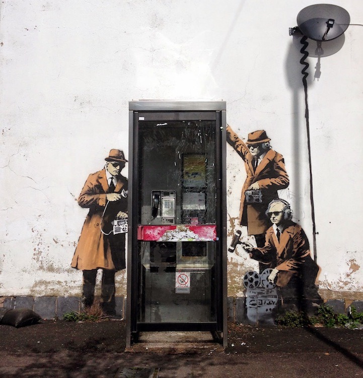 This new street art, depicting three secret agents wiretapping a phone booth, is rumored to be the latest work of Banksy.