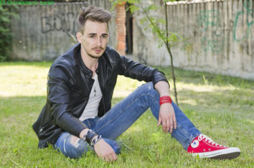 amputee model guy with red converse sneakr on his only leg is sotting on the grass