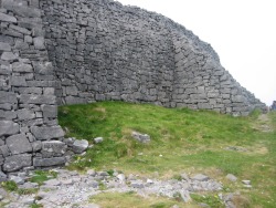 sabreean:  The top photo shows two of the closely-set stone pillars called chevaux de frise, a broad band of which surround the outer side of the middle enclosure wall and are difficult to maneuver around even now (I tripped a few times just getting