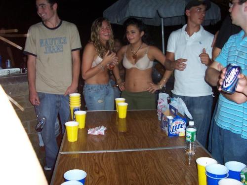 Two girls playing backyard strip beer pong, both end up topless as a result.