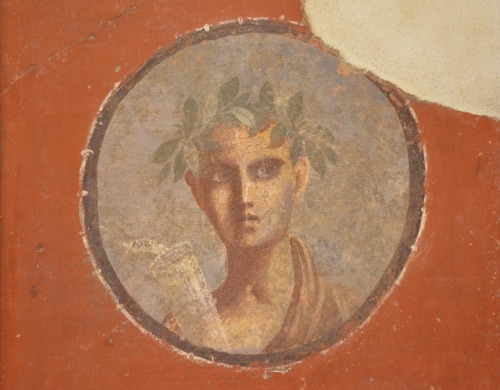 A young man holds a scroll labeled “Plato”.  Fresco from the House of the Apartment, Pompeii; now in