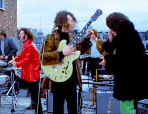 John Lennon And George Harrison Sharing A Cigarette During The Beatles’ Final Live Performance, 1969