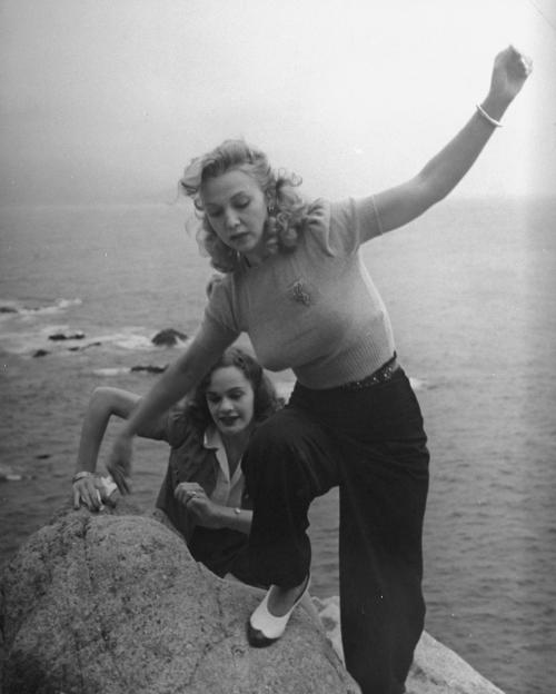 grapnel:Carole Landis and a friend climbing on rocks near the ocean. Photo by Peter Stackpole/The LI
