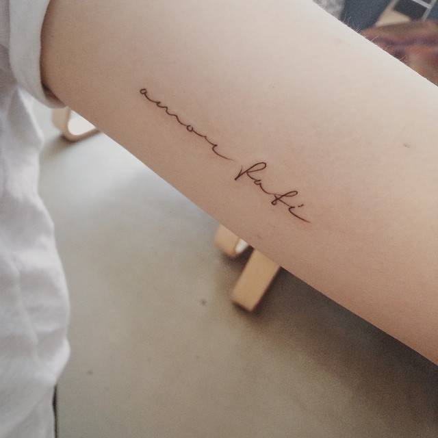 Tatuaje que dice “Amor fati” situado en el interior del brazo izquierdo. Artista tatuador: Doy