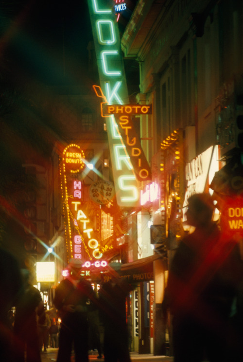 Neon signs blur the night scene as marines walk on the street in San Diego, California, July 1969.Ph