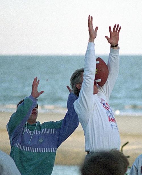 President Bill Clinton misses the ball while playing football on the beach in South Carolina, 1993.