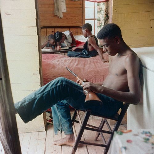 ibethattrillkid:  An African American teen, with his siblings in the background, standing guard with a gun during racial violence in Alabama,1956. 