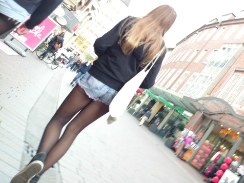 Hot girl in black pantyhose under short denim short caught in the street. Woman in pantyhose