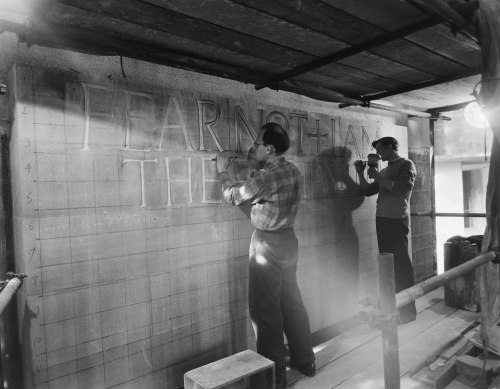 Ralph Beyer and Michael Watson carving an inscription on a stone panel, Coventry Cathedral (via here