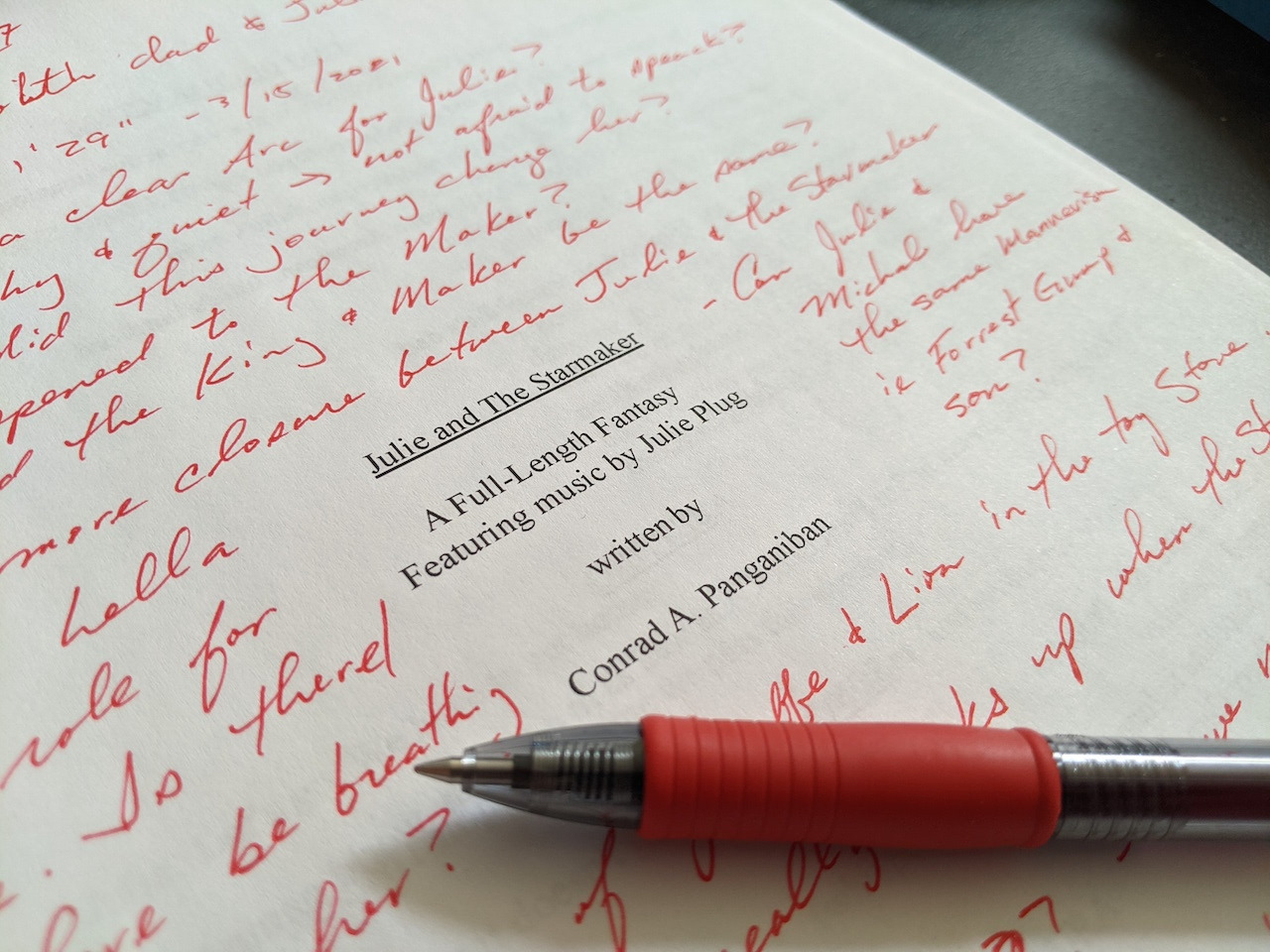 The coversheet for JULIE AND THE STARMAKER with various notes and questions written in red ink with a red pen resting on it.