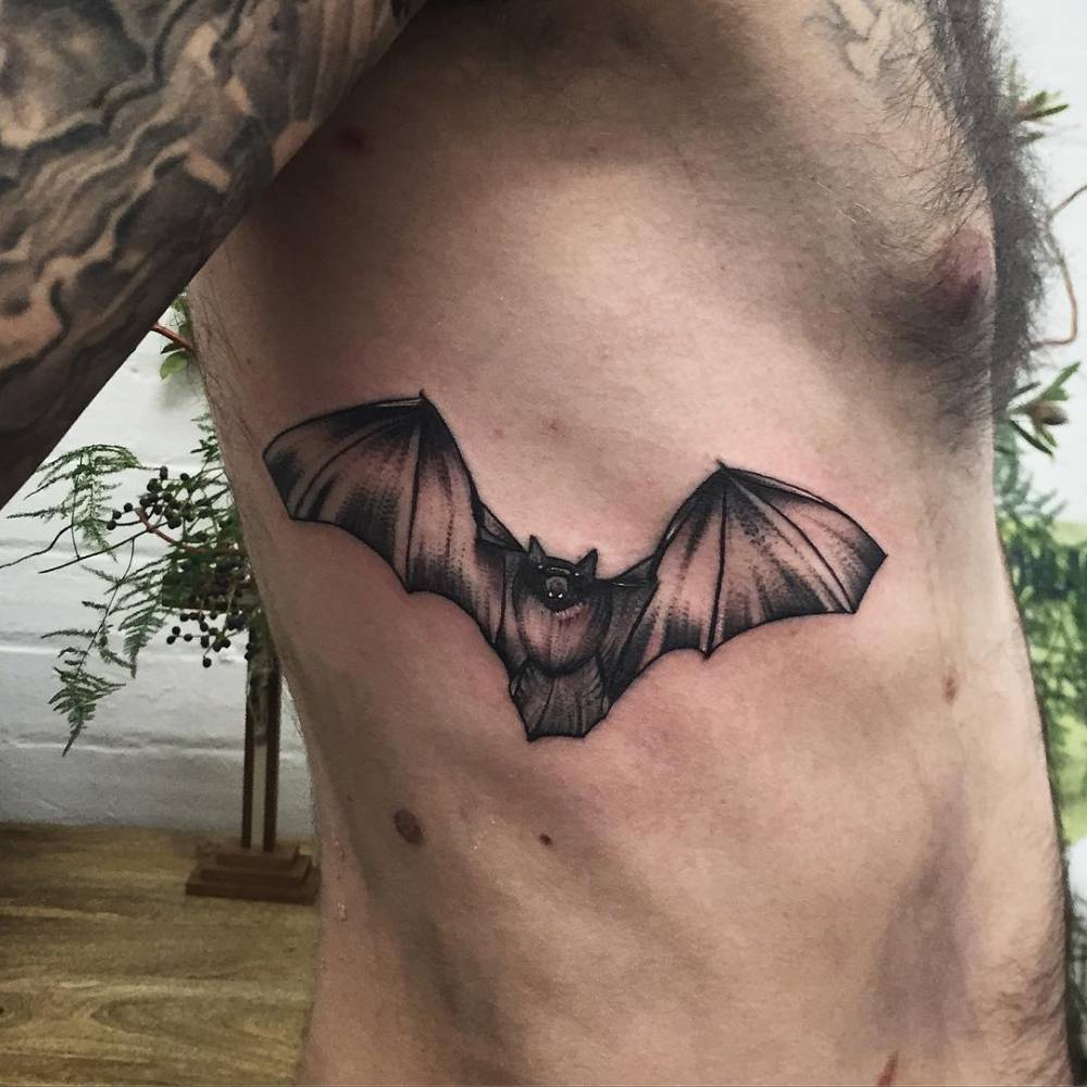Bat tattoo on the left arm.