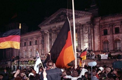 Color photo: People and German flags in front of the Reichstag building in Berlin.  Photo description of the Federal Archives: Hundreds of thousands were there when the black, red and gold federal flag was hoisted in front of the Reichstag.