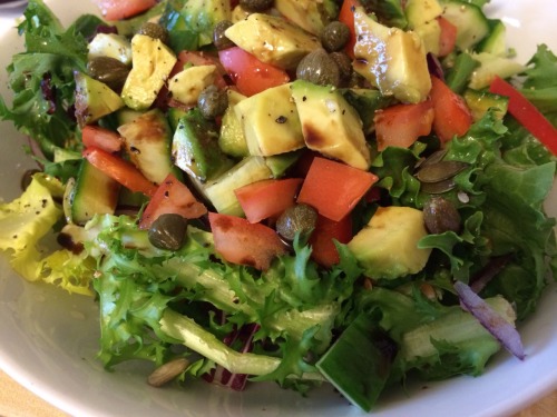 Salad of lettuce, cucumber, tomato, red pepper, red onion, avocado, seeds, capers and vinegar (Home meal)