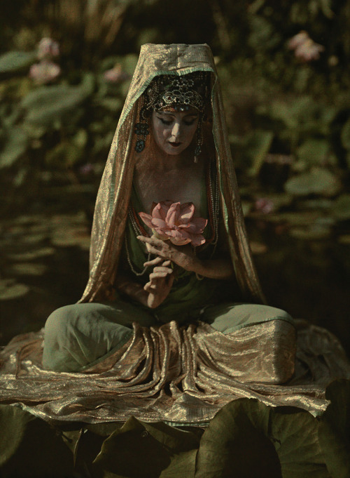 Woman adorned like a Chinese goddess poses in a garden in California, 1915. Photograph by Franklin P