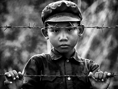 A Khmer Rouge dressed child held at a refugee camp in Thailand, 1998. He and his family had fled fig
