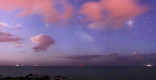 i-belong-to-the-sea:   The Earth’s clouds reflecting moonlight, creating a faint, reddish glow at a beach in northern France. Beyond the clouds lie cosmic dust and star clouds of the Milky Way. The constellation Sagittarius can be seen peaking