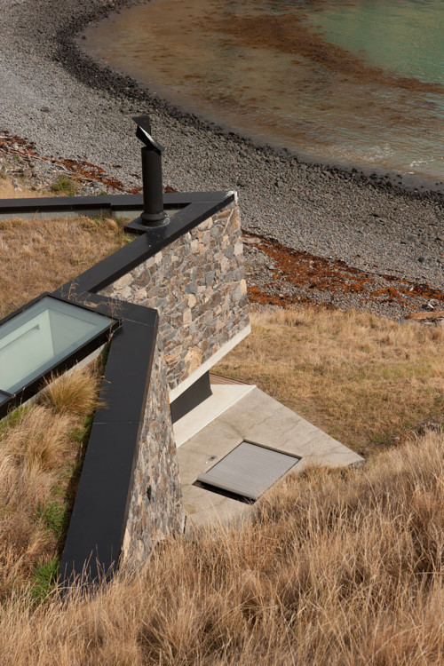 archatlas:    Seascape Retreat    Patterson AssociatesA romantic beachside cottage is set into a rock escarpment in a tiny boulder strewn South Pacific cove. It is a shelter designed as a honeymoon retreat for paying guests consisting of just three rooms,