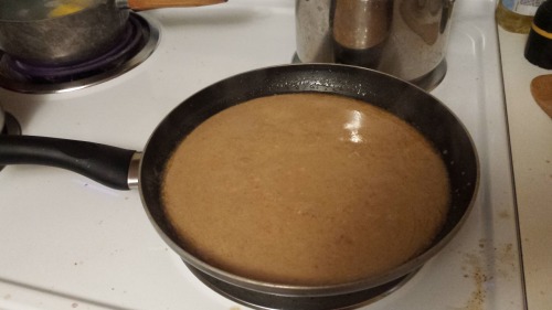 A light brown sauce simmering in a frying pan.