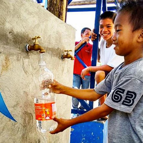 A student at Lapay Elementary School in Tanauan, Leyte, Philippines fills a plastic bottle with clea