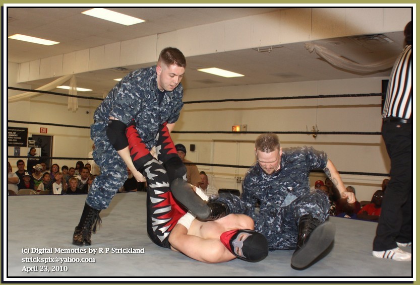 two army dudes take it to the ring vs the shirtless masked dude. they double him, on army dude holding his legs while the other drops a big leg drop across his chest!
then they hoist him up, put one arm around each of their necks and hoist him up in...