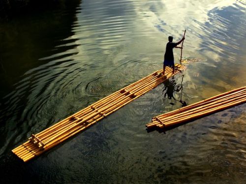 Photograph by Gerardo Sabado | A boatman paddles his bamboo raft along the river at Wawa Dam, Philip