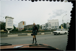 View On The New Russia: A Car’s Windshield, Held In Place By Coins, Frames A Woman