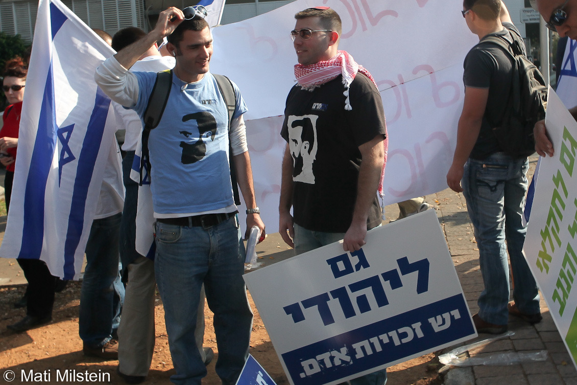 Identity Crisis
“ The far-right Im Tirzu movement prepares to participate in the International Human Rights Day march in Tel Aviv. The activist on the right, who wears both a Jewish skullcap and a Palestinian keffiyeh, holds a sign reading “A Jew...