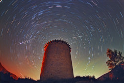 inothernews:  SLINGS, NOT ARROWS   At least five meteors, part of the annual Leonid meteor shower, are photograhed streaking high above the Torre de la Guaita, an observation tower used during the 12th century in Girona, Spain.  (Photo: Juan Carlos