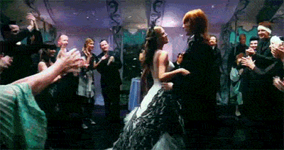 Bill and Fleur dance at their wedding. The people around them clap as confetti falls from the ceiling.