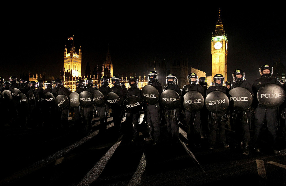 Police officers in riot wear contain student protesters on Westminster Bridge on