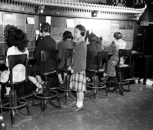 Miss Lucy Tom, chief operator, looks on as telephone operators man their boards in the Chinatown Tel